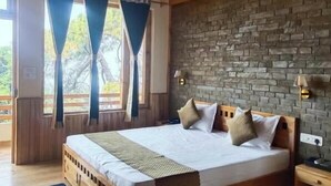 A wooden-paneled bedroom with a brick wall, a large bed, and a ceiling fan. - Kasar Hill Top (Almora)