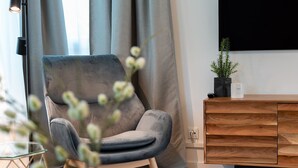 A modern living room with a grey armchair, a wooden sideboard, and a potted plant.