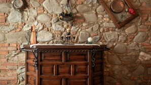 A rustic stone wall with a wooden cabinet featuring a candle holder and a decorative item. - Luna Apartment with Swimming Pool (Porcari)