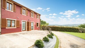 A red building with multiple windows and doors, a concrete driveway, and a well-maintained lawn. - Luna Apartment with Swimming Pool (Porcari)