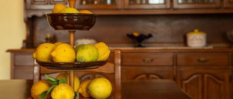 A three-tiered fruit stand with lemons and limes on a wooden table in a kitchen with wooden cabinets.