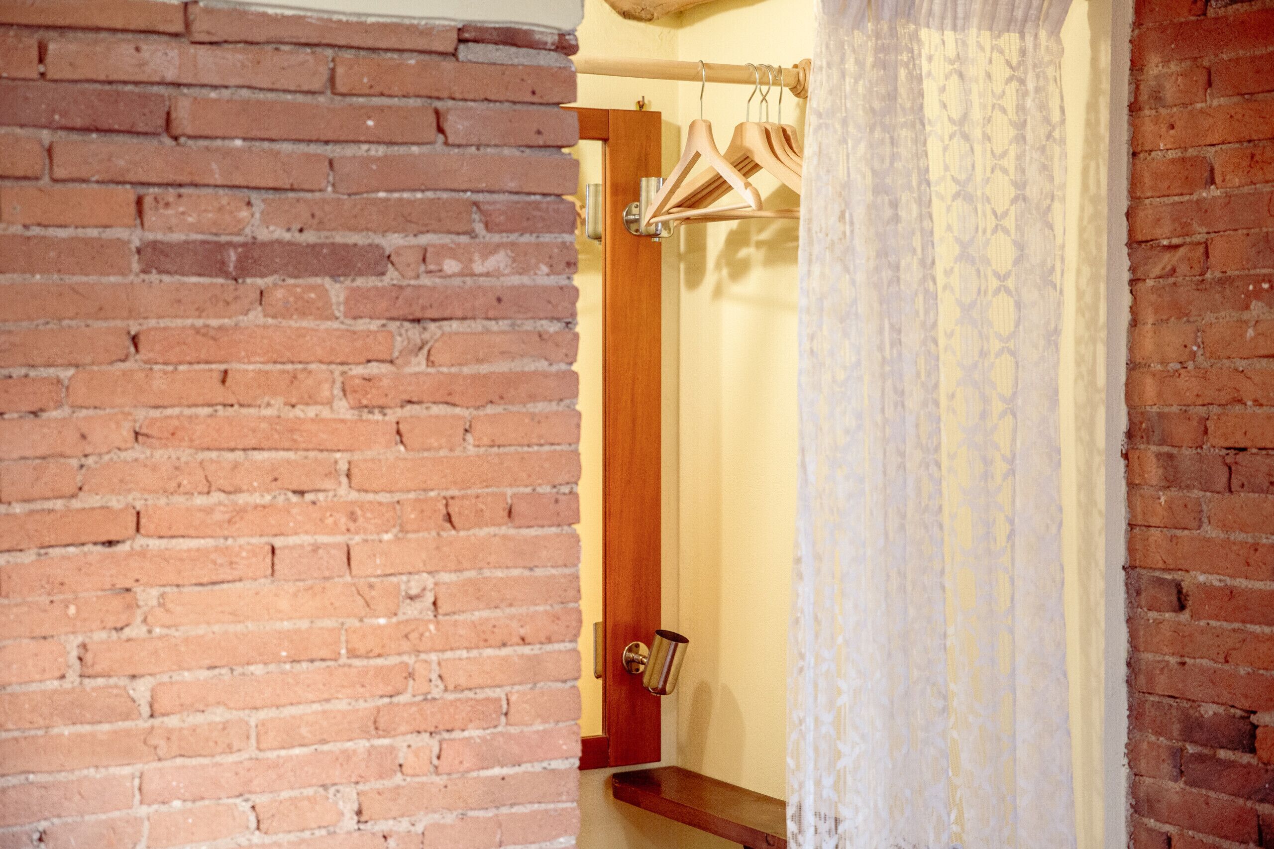 Un mur de briques, une porte en bois et un rideau blanc.