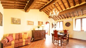A spacious living area with a wooden ceiling, a dining table with chairs, a sofa, and a cabinet.