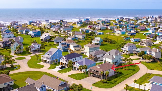 A residential area with houses, roads, and a view of the ocean.