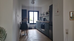 A narrow kitchen with a dining area, a window, and a ceiling light.