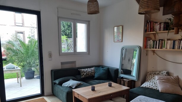 A living room with a sofa, a coffee table, a bench, a bookshelf, and a large window.
