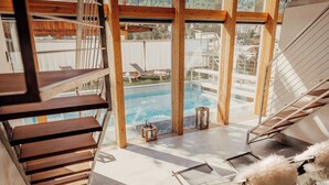 A modern interior with a wooden staircase, a pool area, and lounge chairs. - Backstage Hotel Serviced Apartments (Zermatt)