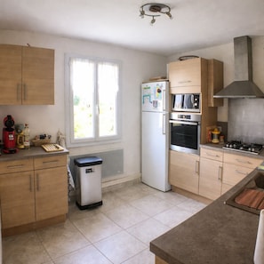 A kitchen with wooden cabinets, a refrigerator, a microwave, an oven, and a gas stove. - Havre de Paix Pour Moments en Famille ou Entre Amis à 10 Min. D'uzès (Baron)