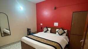 A bedroom with a bed, a ceiling fan, a wardrobe, and a mirror. - Hotel Shri Ram By GRB (New Delhi)