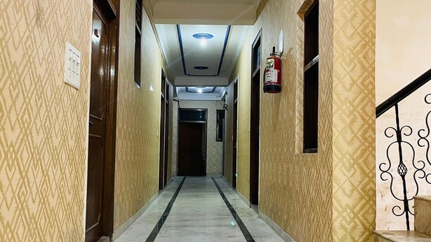 A hallway with patterned walls, a marble floor, and a ceiling with recessed lighting. - Hotel Shri Ram By GRB (New Delhi)