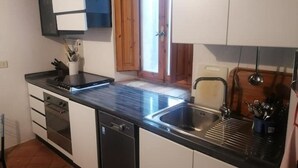 A kitchen with a black countertop, stainless steel sink, and white cabinets.