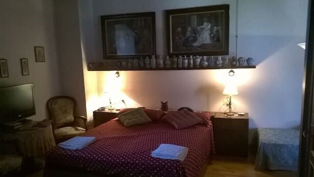 A bedroom with a bed, two nightstands with lamps, a chair, and a television.