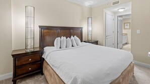 Ein Schlafzimmer mit einem großen Bett, einem Holzkopfbrett, Nachttischen und einem Spiegel.