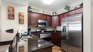 Una cucina moderna con mobili in legno scuro, elettrodomestici in acciaio inossidabile e decorazioni a parete.