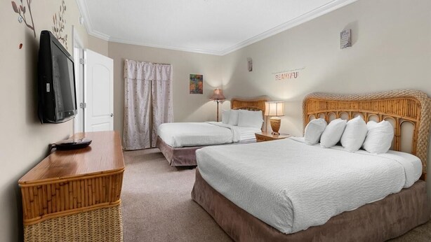 Ett hotellrum med två sängar, en tv, ett skrivbord och en fåtölj i rotting.