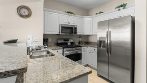 A modern kitchen with white cabinets, a stainless steel refrigerator, a microwave, and a stove. - Sun Sand Seclusion 2BR Oceanfront Condo Jetted Tub (North Myrtle Beach)