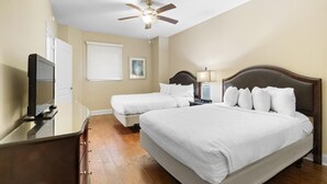 A hotel room with a large bed, a smaller bed, a desk with a computer, a ceiling fan, and a window with blinds. - Beachfront Elegance: 2BR Condo with Jetted Tub (North Myrtle Beach)