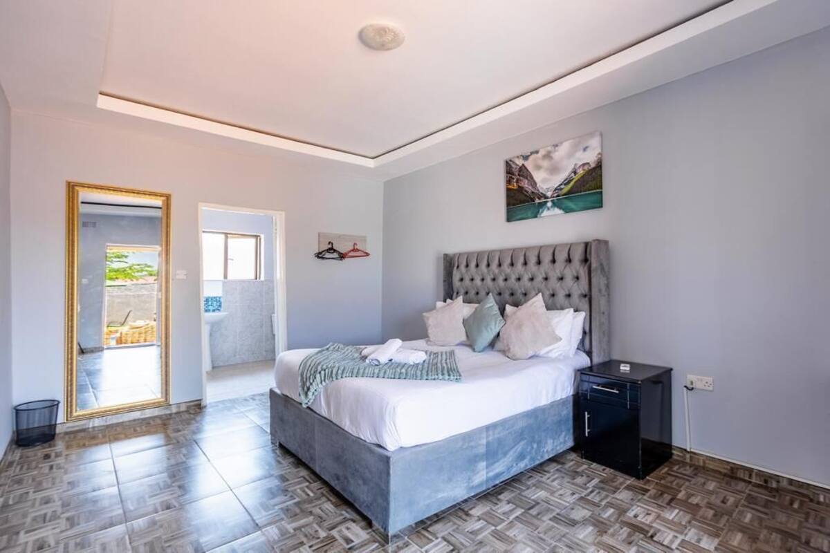 Ein Schlafzimmer mit einem großen Bett, einem Nachttisch, einem Bild an der Wand und einer Tür, die zu einem Außenbereich führt.