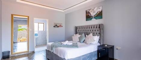 Un dormitorio con una cama grande, una mesita de noche, un cuadro en la pared y una puerta que da a un área exterior.