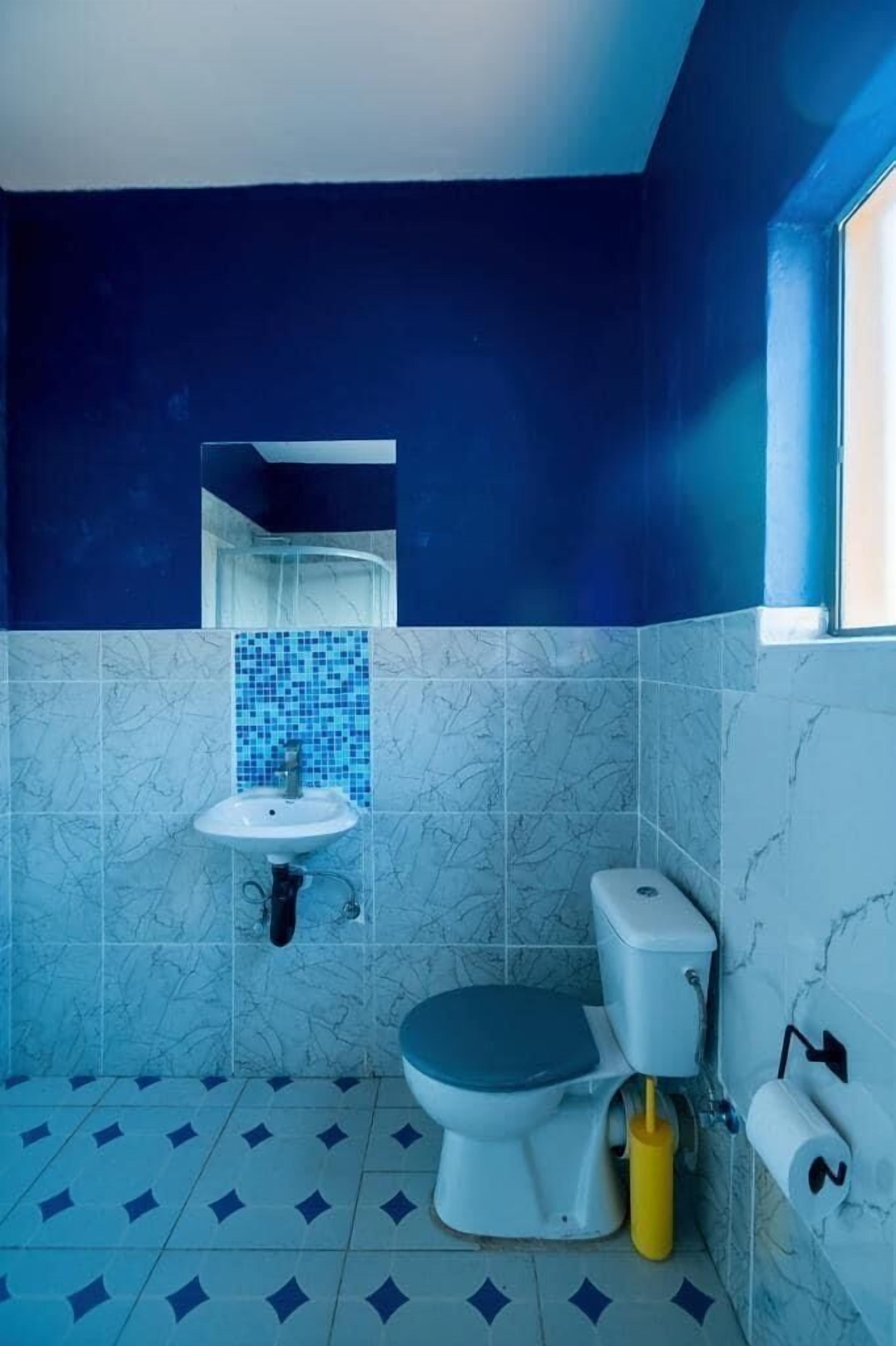 A bathroom with a toilet, sink, and a blue-tiled shower area.