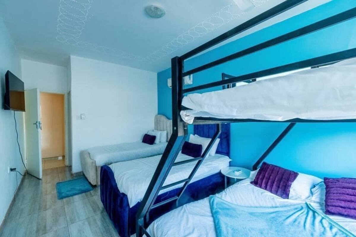Ein Zimmer mit Etagenbetten, einem kleinen runden Tisch und einem Fernseher an der Wand.
