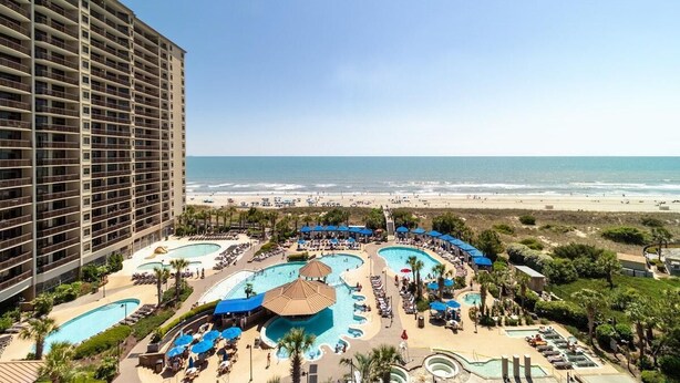 A hotel with multiple swimming pools and a beach view.