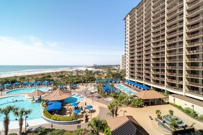 Ein Hotel mit mehreren Schwimmbecken, Blick auf einen Strand und einem großen Gebäude mit Balkonen.