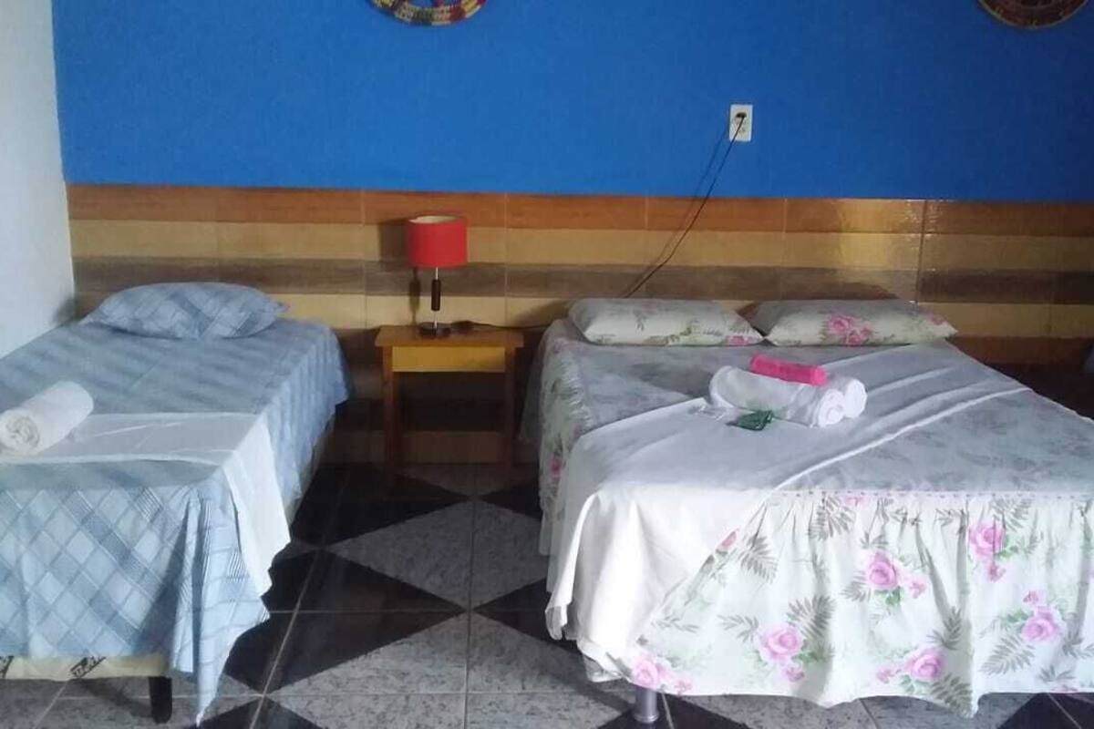 A hotel room with two single beds, a nightstand with a red lamp, and a checkered floor.