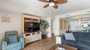 A living room with a television, a sofa, a coffee table, and a ceiling fan.