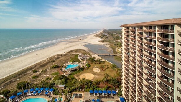 A beachfront hotel with multiple balconies, a pool, and a beach view. - Penthouse Elegance by the Sea 3BR Condo with Views (North Myrtle Beach)