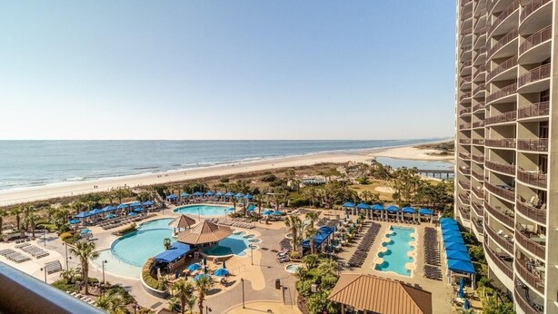 A resort with a large pool area, multiple swimming pools, and a beach view.