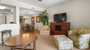A living room with a dining area, a television, and a plant.