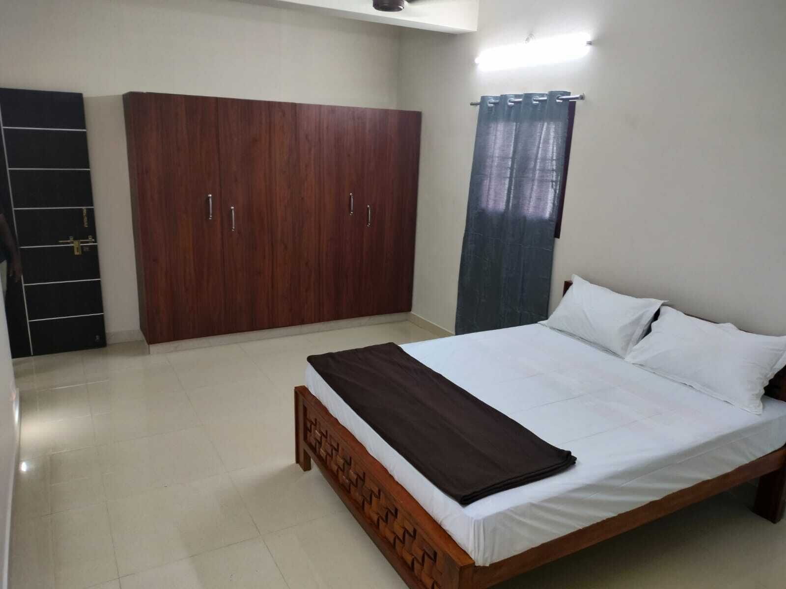 A bedroom with a wooden bed, a wardrobe, and a curtain.