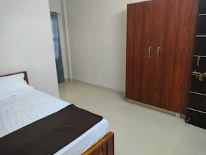 A bedroom with a bed, a wooden wardrobe, and a door with a lock.