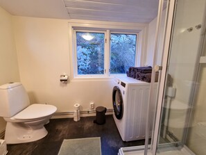 Enjoy a refreshing shower in this bathroom featuring a glass enclosure, washing machine, and a window with a view.