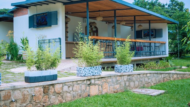 A modern house with a covered porch, stone wall, and potted plants. - Don Bosco Hospitality Centre (Kigali)
