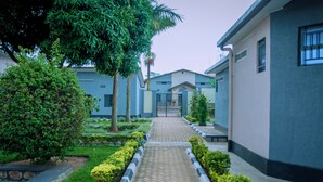 A pathway leading to a gated entrance of a building with a modern architectural style, surrounded by well-maintained greenery and a stone border. - Don Bosco Hospitality Centre (Kigali)