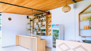 A bar area with wooden shelves stocked with bottles, a refrigerated display case, and a counter. - Don Bosco Hospitality Centre (Kigali)