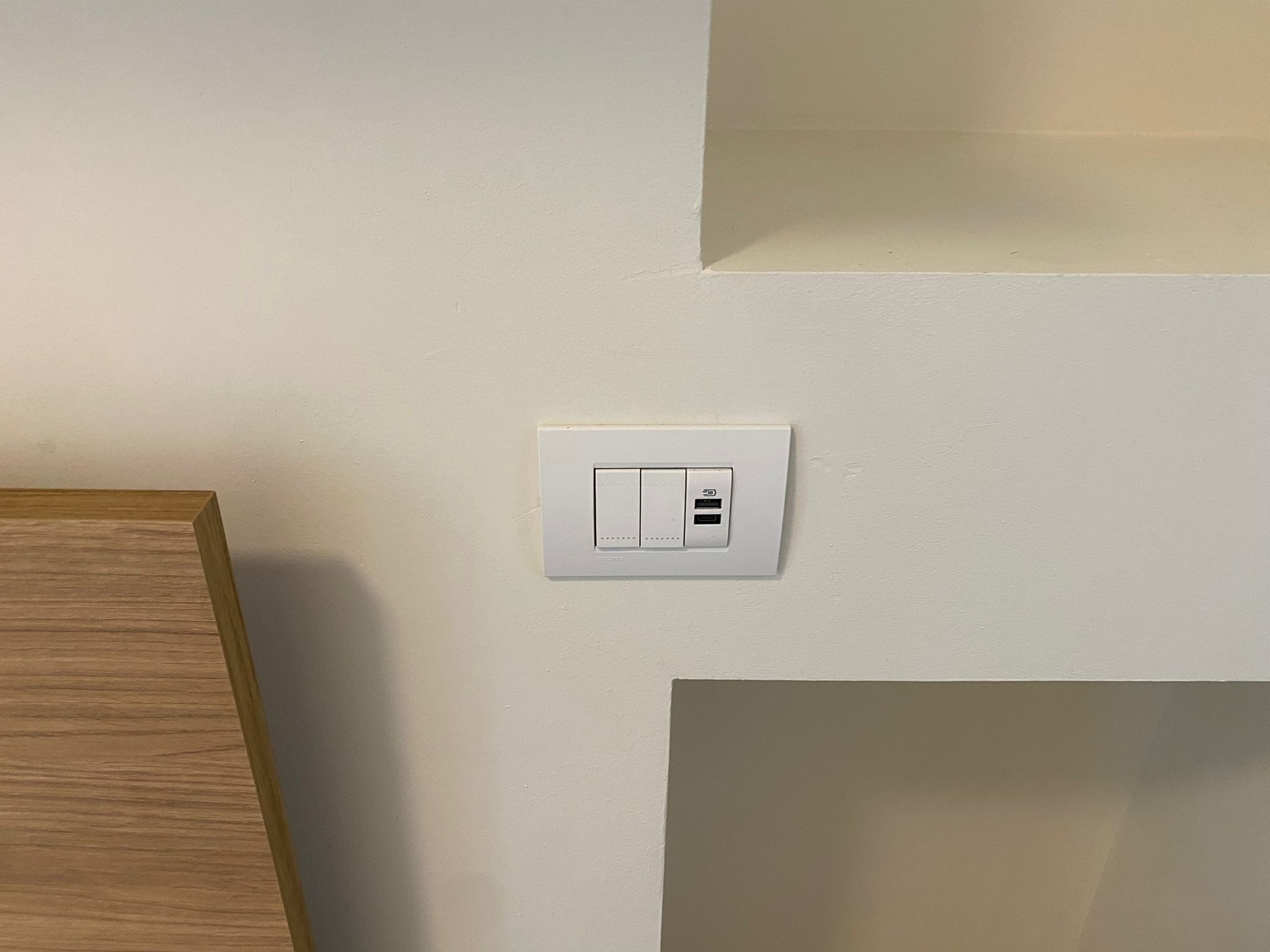 A white electrical outlet with a USB port on a plain wall.