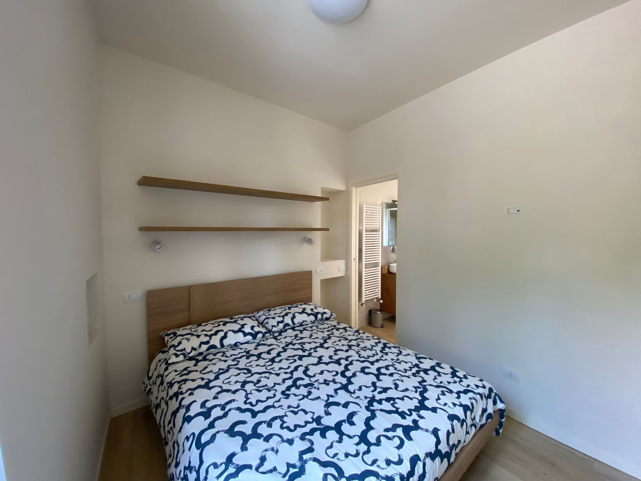 Une chambre à coucher avec un lit, une tête de lit en bois et des étagères intégrées.