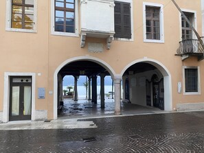 A building with a covered entrance, arched doorways, and a view of the sea. - Residenza Flavia (Salò)