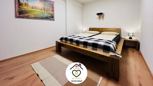 Ein Schlafzimmer mit einem hölzernen Bett, einem Nachttisch, einer Wand-Klimaanlage und einem Landschaftsbild.