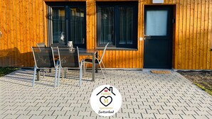 Ein Holzhaus mit einer Terrasse, ausgestattet mit einem Tisch und Stühlen.