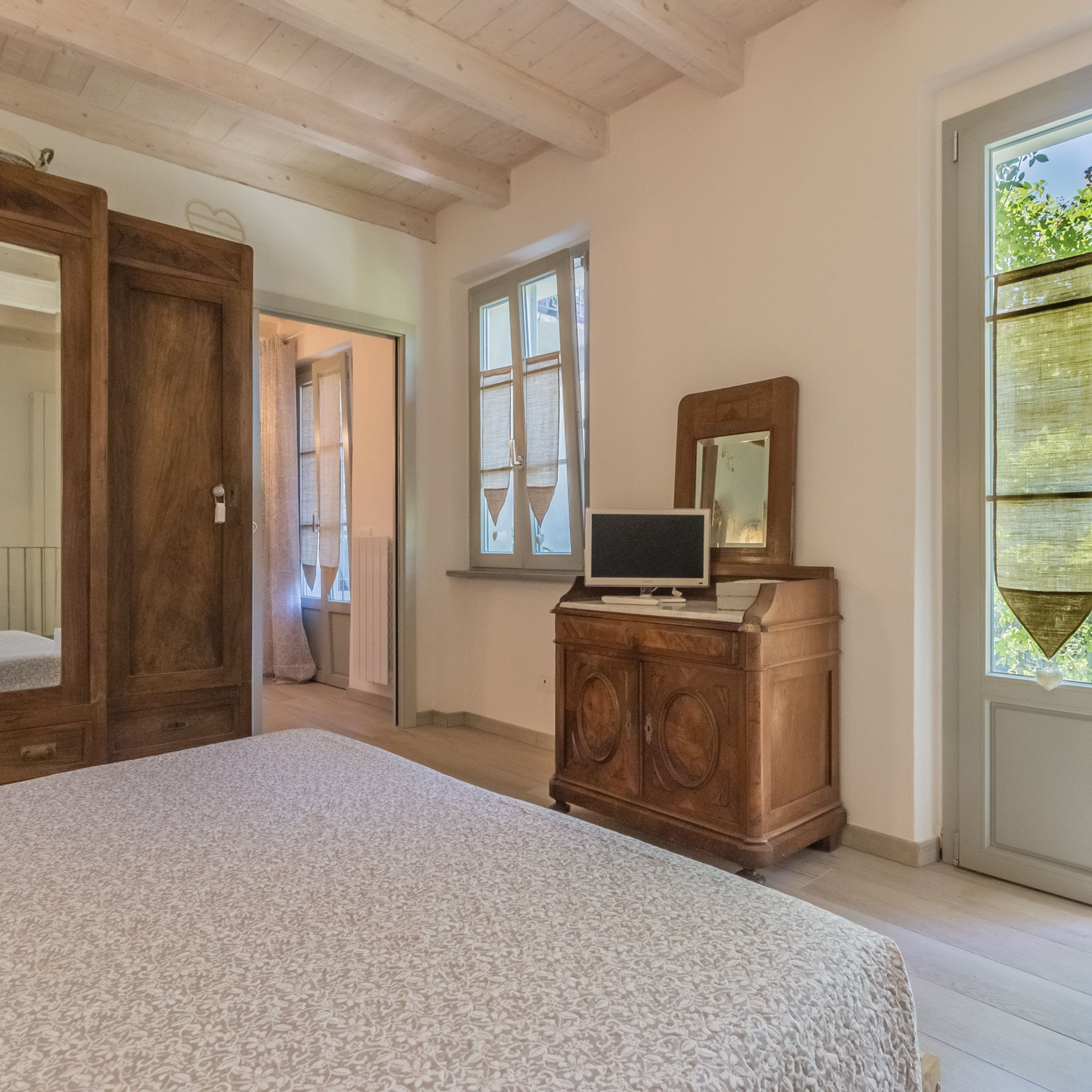 A bedroom with a bed, a dresser, a television, and a window.