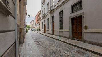 A cobblestone street lined with historic buildings, featuring a variety of architectural styles and a narrow sidewalk.