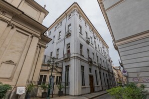 A corner building with classical architecture, featuring a balcony and a door.