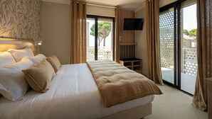 Una camera da letto con un letto grande, una TV montata a parete e una porta vetrata scorrevole che dà su un balcone.