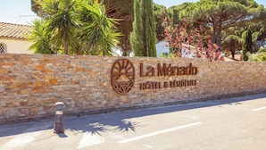 Un muro di pietra con un cartello per l'Hotel & Residenze La Menda.