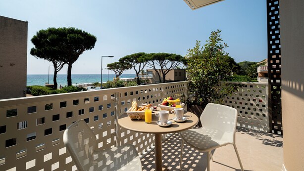 Un balcone con un tavolo apparecchiato per la colazione, vista mare.