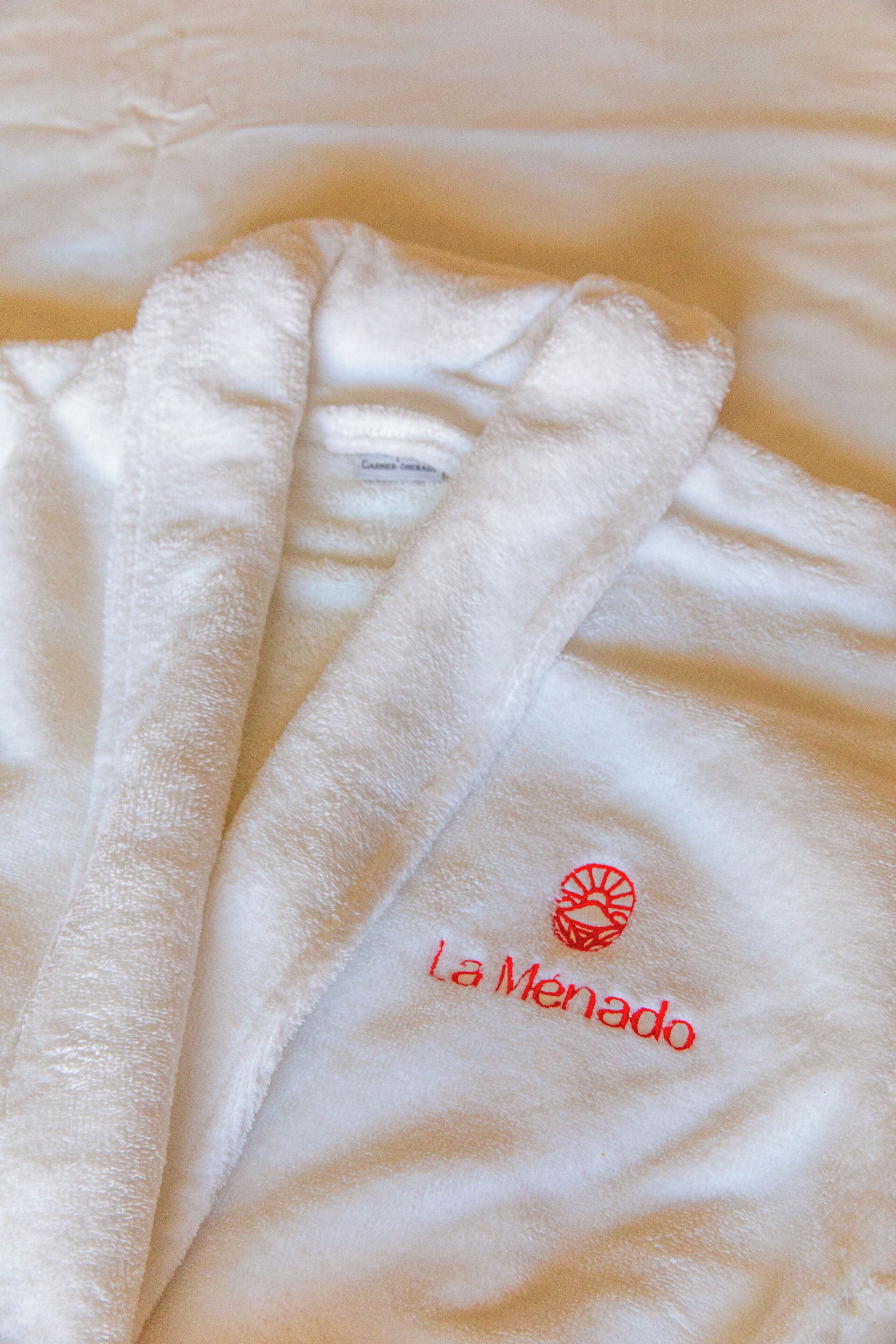 Una toalla blanca con el bordado 'La Menado' en rojo.